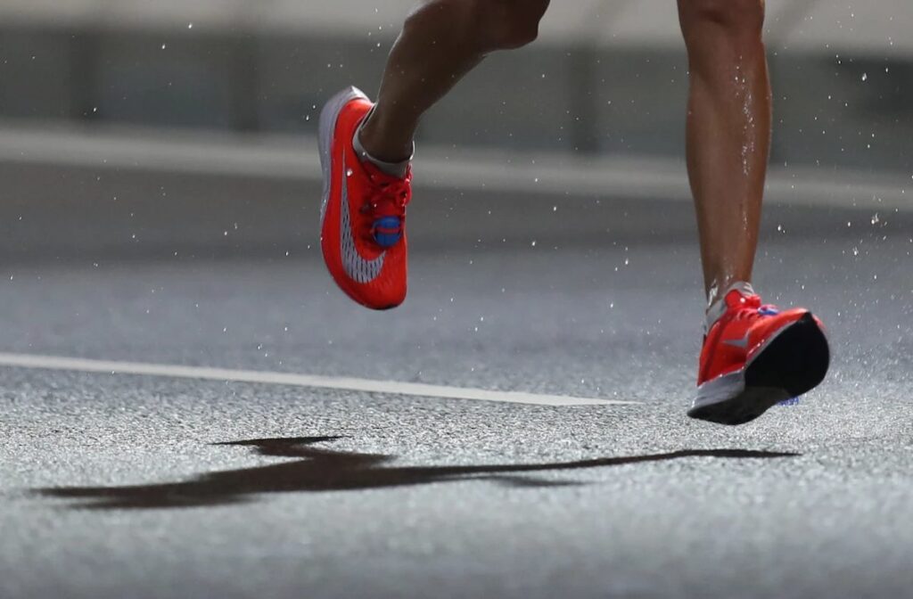 vista de frente de um atleta correndo na pista com um tênis de placa de propulsao