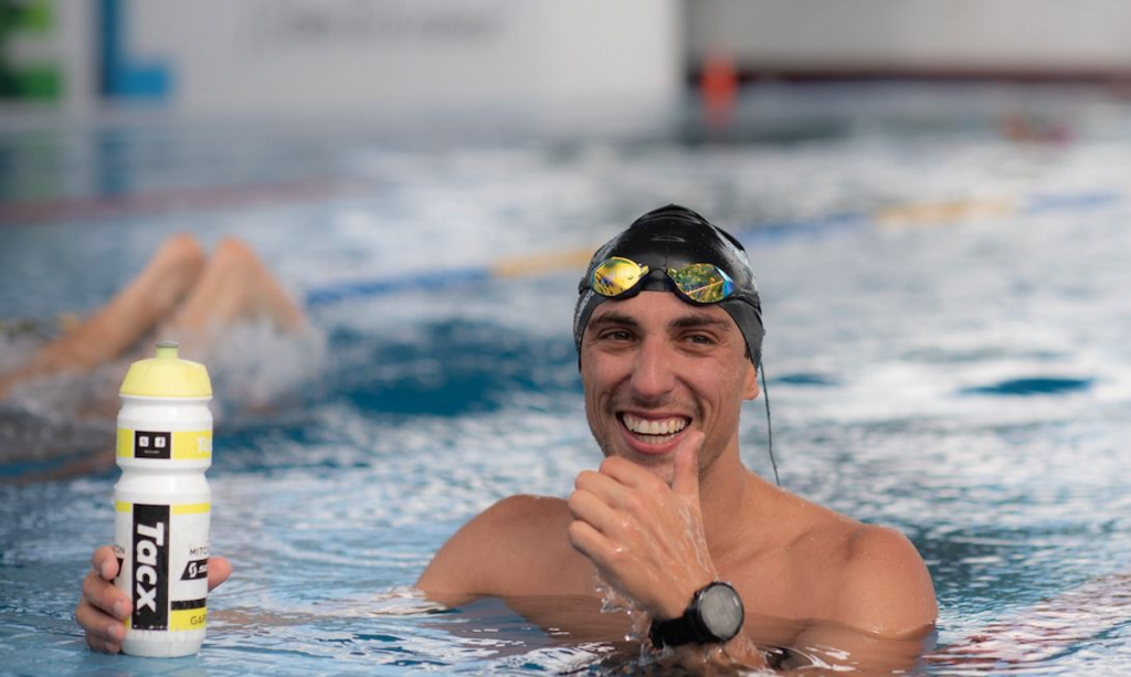 atleta na piscina sorrindo com uma touca de natação