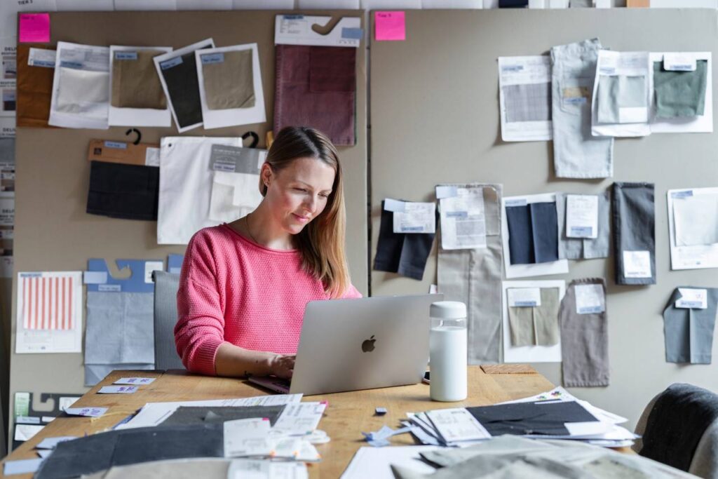 mulher sentada em uma mesa de escritório com uma feição sorridente olhando para o computador