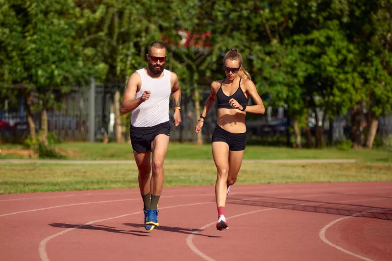 Casal correndo em pista de atletismo ao ar livre
